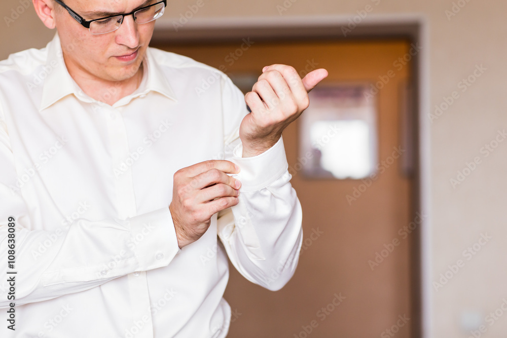 Business man fastening buttons on shirt sleeve at home close-up Business man fastening buttons on shirt sleeve at home close-up