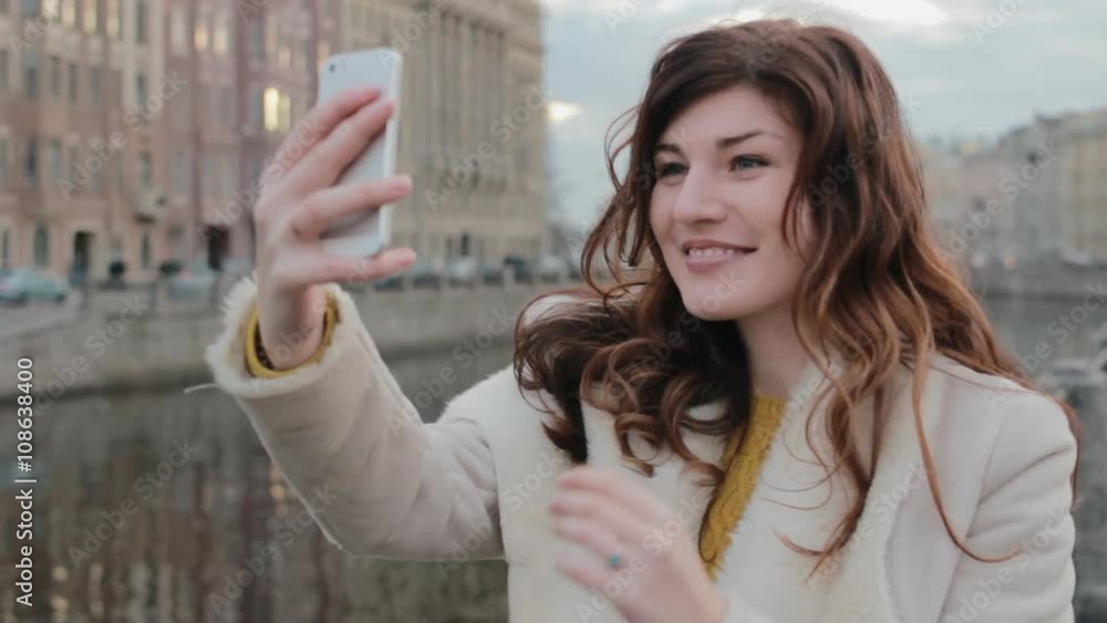 Attractive young woman taking selfie in the old town beside a river Attractive young woman taking selfie in the old town beside a river