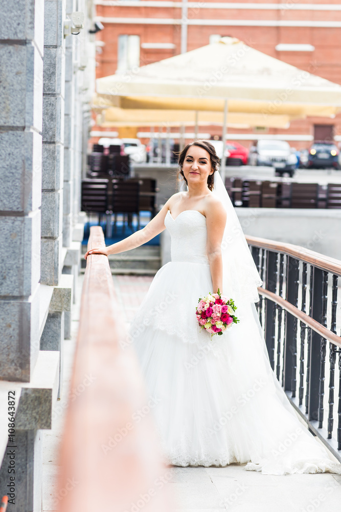 Fototapeta premium Young bride in wedding dress holding bouquet