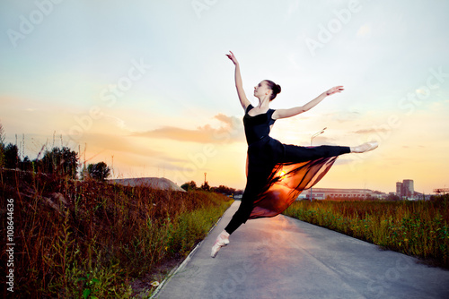 Beautiful ballerina in black skirt and leotard on street road.