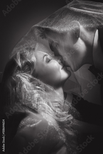 Wedding couple indoors is kissing each other on black-and-white