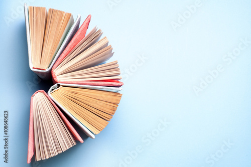 Top view of bright colorful hardback books in a circle. Open book, fanned pages. Education essential for self improvement, gaining knowledge and success in our careers, business and personal lives.