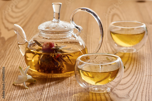 Glass teapot and two cups with green tea