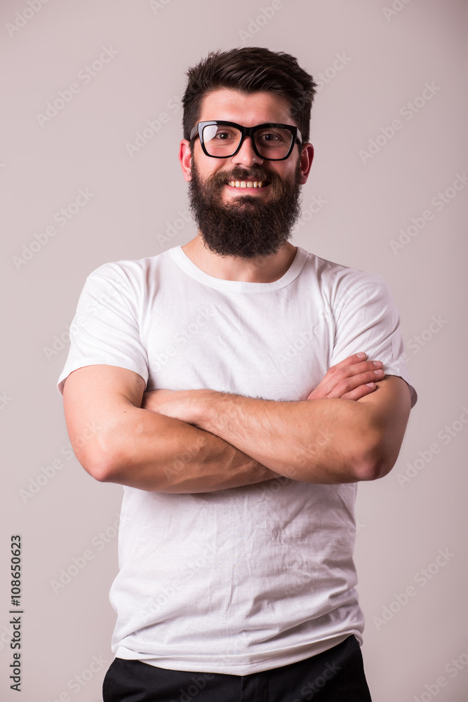 Bearded man in glasses with crossed hands look at camera on white Bearded man in glasses with crossed hands look at camera on white
