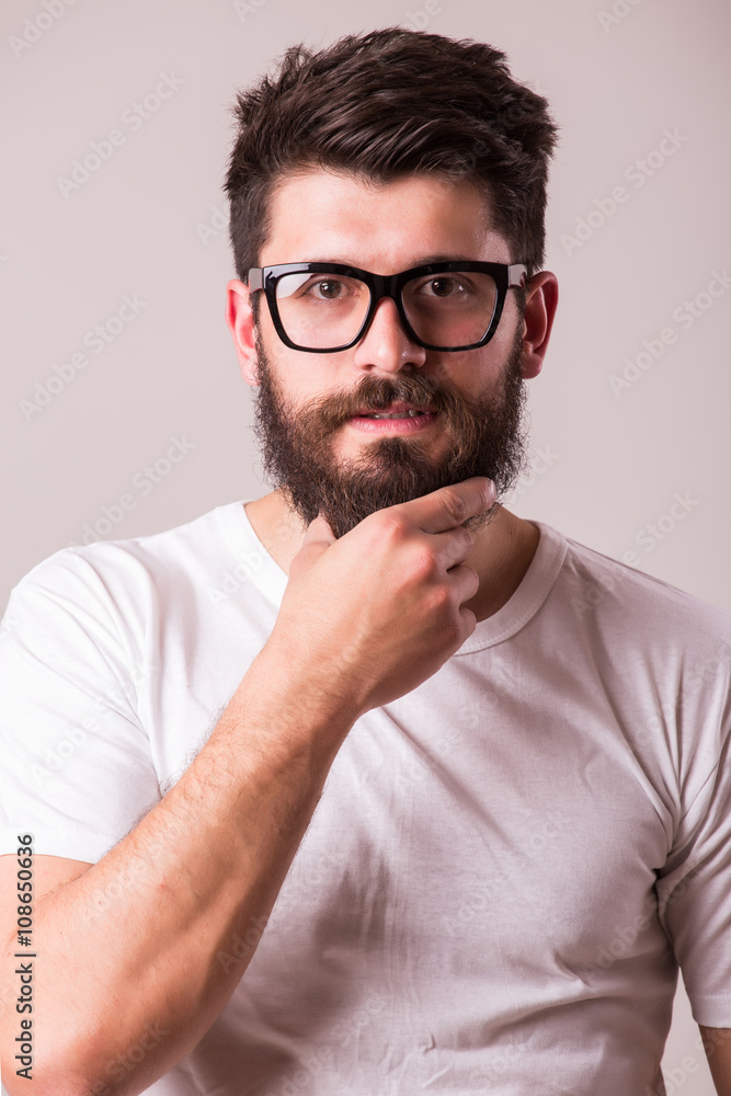 Fototapeta premium Face portrait of bearded man in glasses with hand on beard against white background