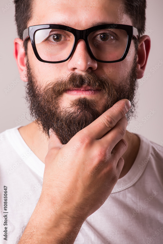 Face portrait of bearded man in glasses with hand on beard against white background Face portrait of bearded man in glasses with hand on beard against white background