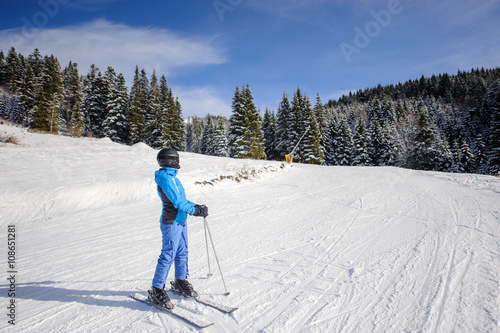 Wide shot of female skier on a ski slope at ski resort on a sunny day. Winter sports concept. Carpathian Mountains, Bukovel, Ukraine