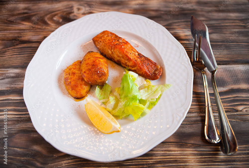 Grilled Salmon with potatoes, slice of lemon on wooden backgroun Grilled Salmon with potatoes, slice of lemon on wooden backgroun