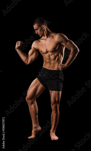 Sexy Athletic Man showing six pack abs. Isolated on black background with copy space