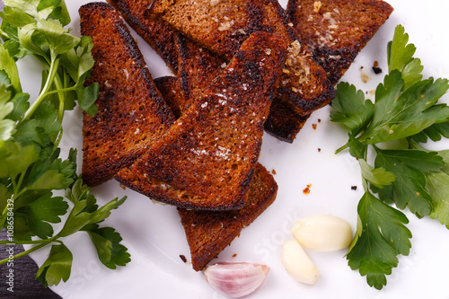 Roasted salted garlic croutons with fresh parsley and piese of  garlic on white plate. photo