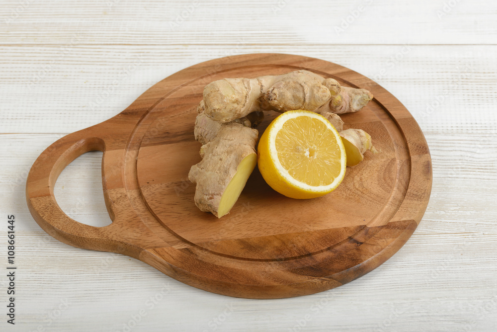 Combination of yellow lemon half and ginger laid out on a wooden cutting board . Ingredients to take for colds. Combination of yellow lemon half and ginger laid out on a wooden cutting board . Ingredients to take for colds.