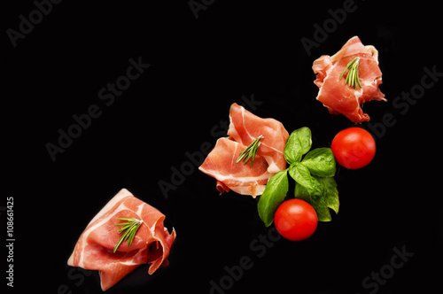 sliced prosciutto isolated on black background