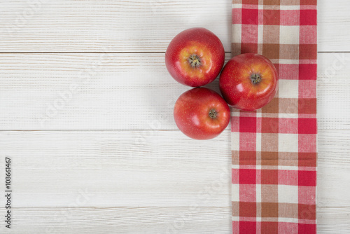 Apples placed on red checkered kitchen tablecloth. Top view.