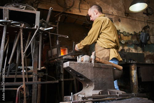 The wizard removes the excess weld using a power saw with a metal layout of a construction crane