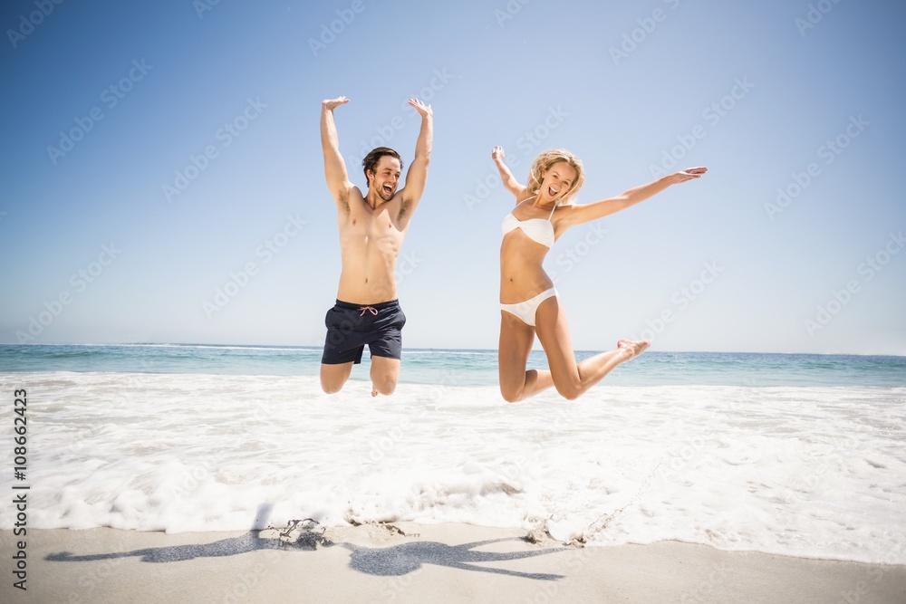 Happy couple jumping on the beach