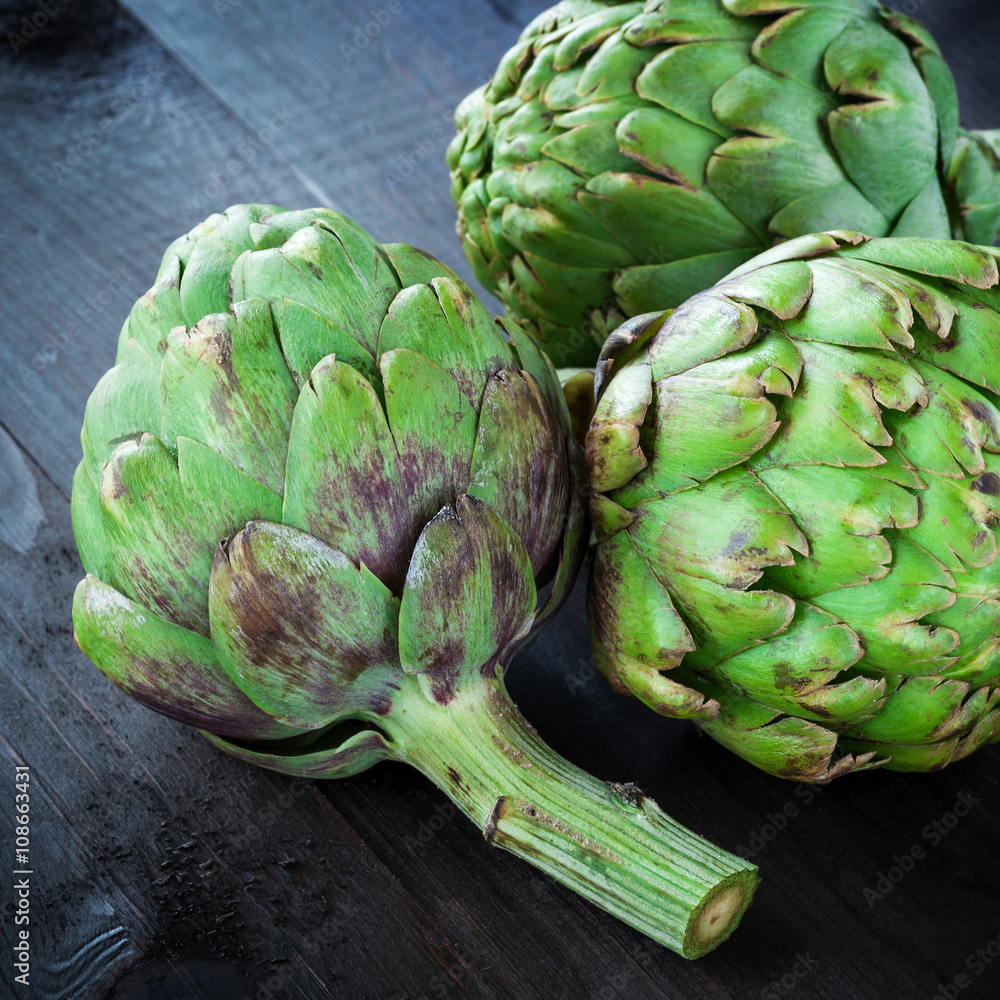 Obraz premium Fresh green artichokes on wooden table