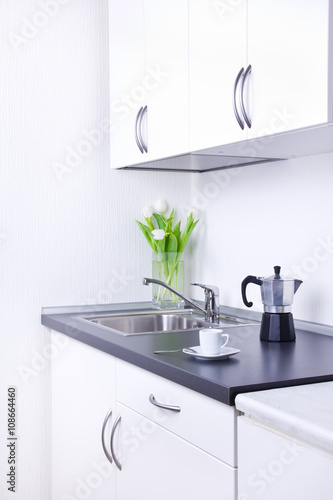 Percolator and cup of coffee on worktop, kitchen interior