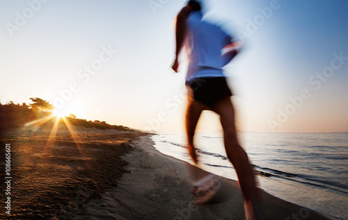 Young man running on a beach at sunrise. Motion blur effect. Concepts: well-being, vitality, healthy life, vacation, sport, training