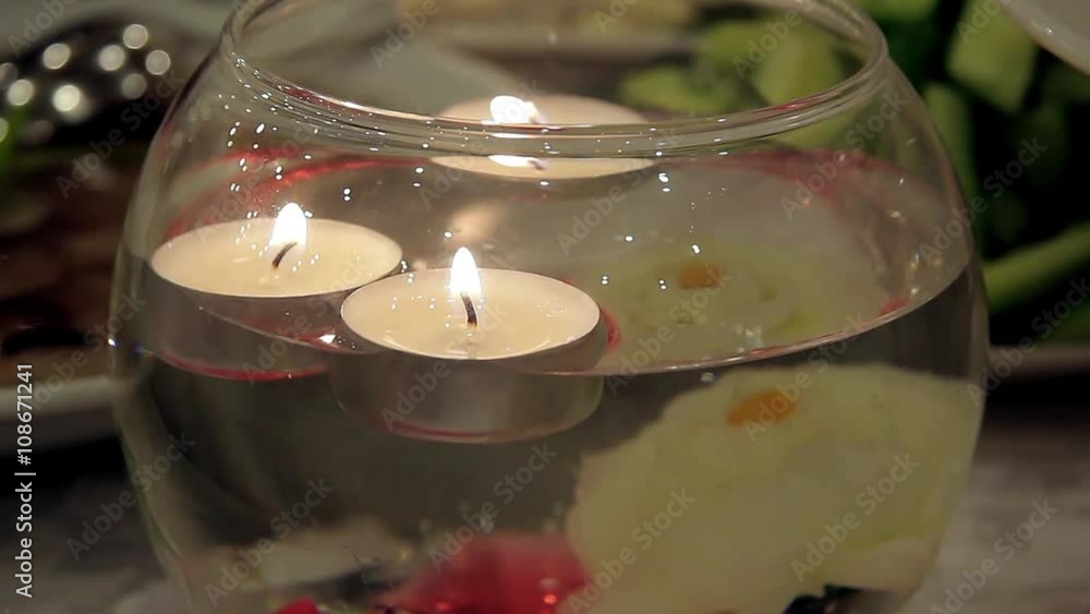 Burning candles floating in a decorative vase Burning candles floating in a decorative vase