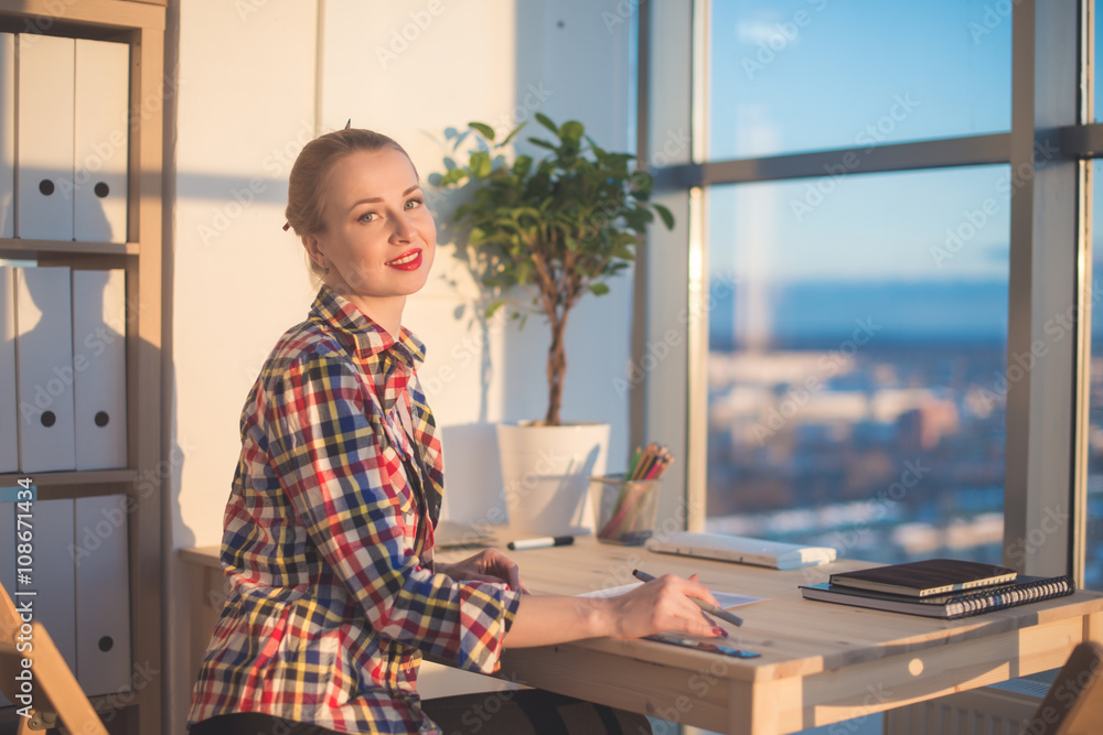 Fototapeta premium Side view of happy young woman working in home office, writing on paper. Female student learning material, doing task at workplace.