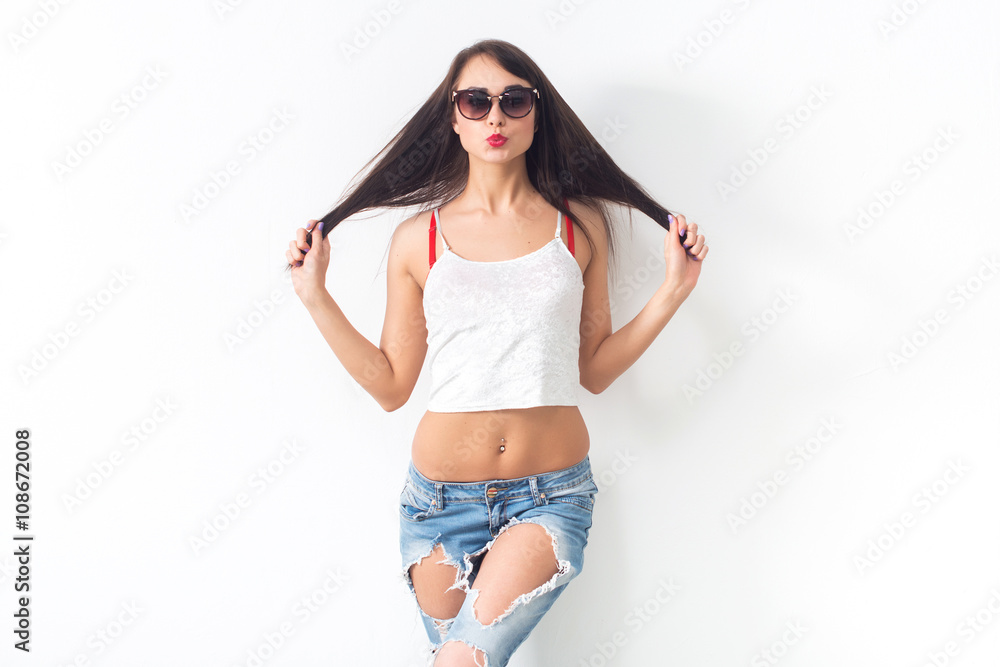 Front view studio portrait of a young cute model wearing sunglasses and ripper jeans, doing duck lips, looking at camera, not isolated. Front view studio portrait of a young cute model wearing sunglasses and ripper jeans, doing duck lips, looking at camera, not isolated.