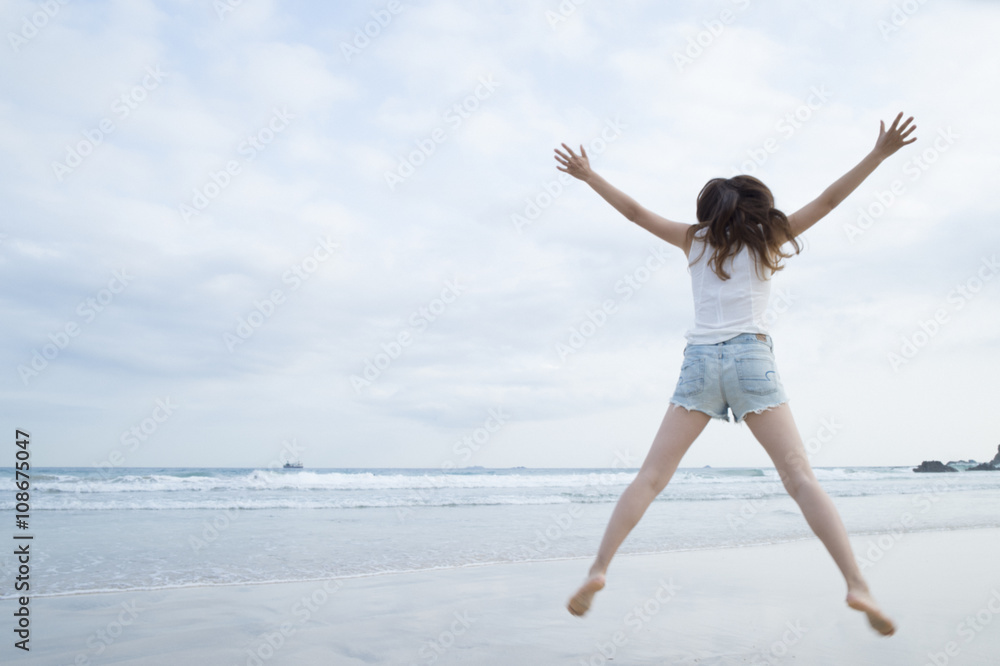 Women have to jump with open arms at the beach Women have to jump with open arms at the beach