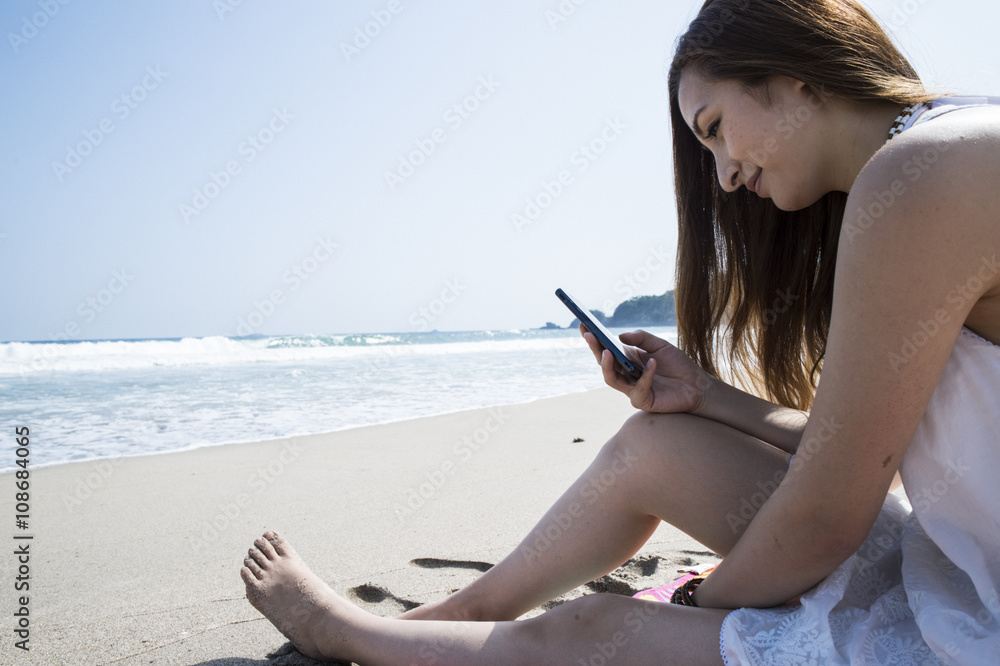 Woman looking at the smartphone at the seaside