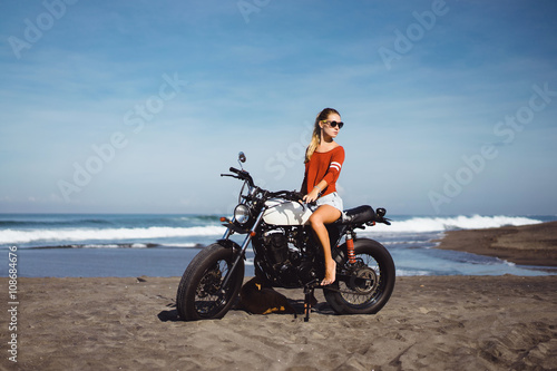 young pretty hipster girl Biker girl sitting on vintage custom motorcycle Biker girl sitting Outdoor lifestyle portrait. jeans short denim, fashion style