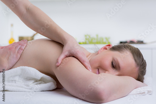 entspannte frau erhält schultermassage im spa