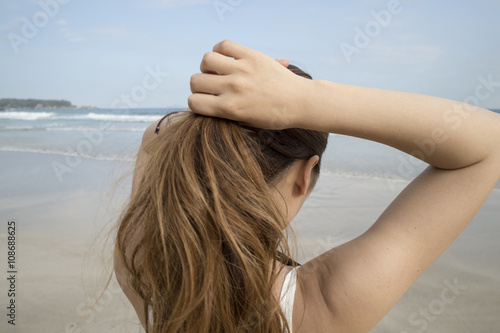 Women are bundled the long hair while looking at the sea