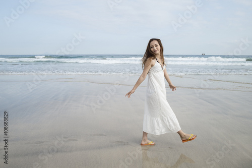 Woman wearing a white long dress is a walk in the seaside
