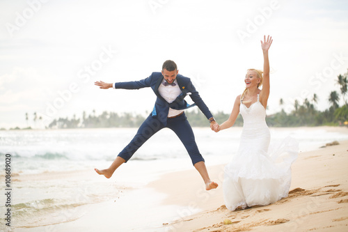 bride and groom playing on the beach