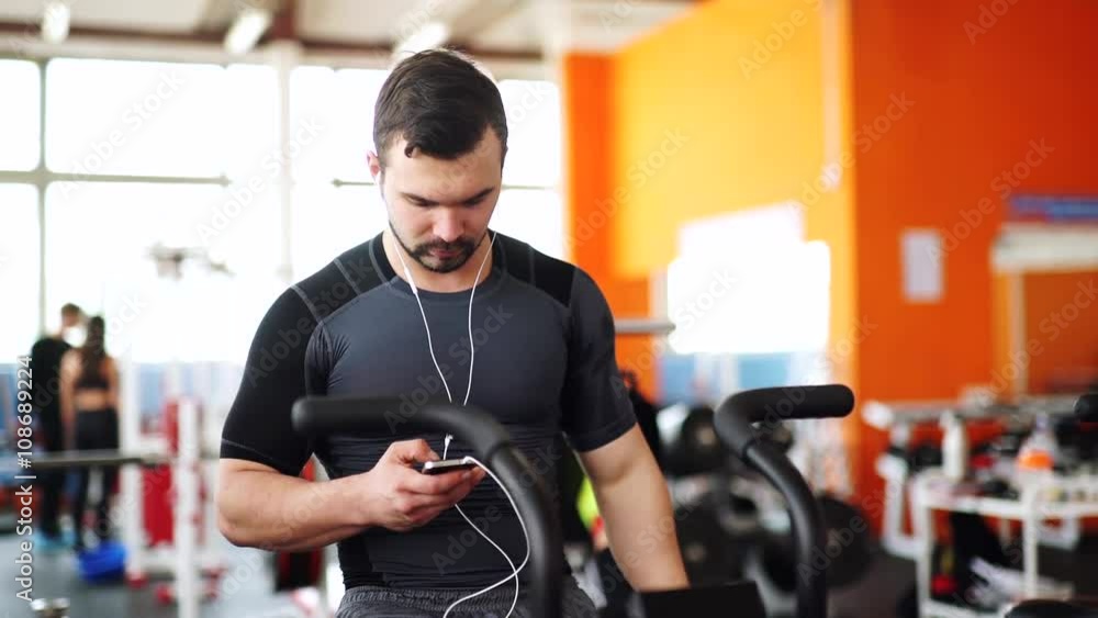 Smiling man on cycle using smart watch at the gym Smiling man on cycle using smart watch at the gym