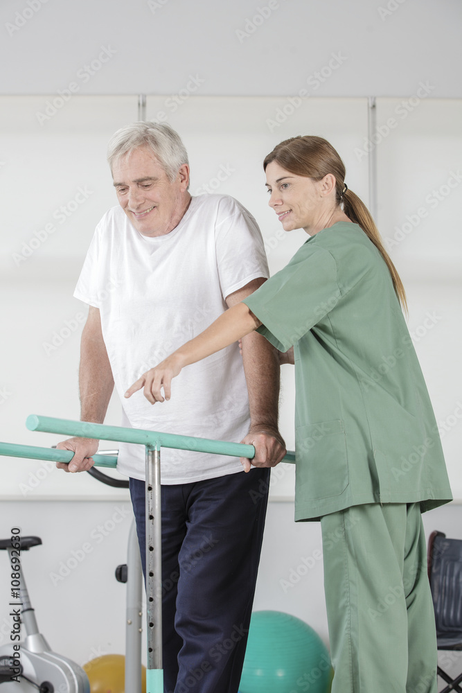 Senior man walking with therapist help in rehab studio Senior man walking with therapist help in rehab studio