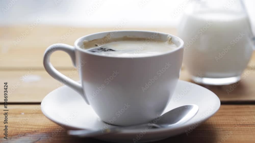 sugar falling into cup of coffee on wooden table sugar falling into cup of coffee on wooden table