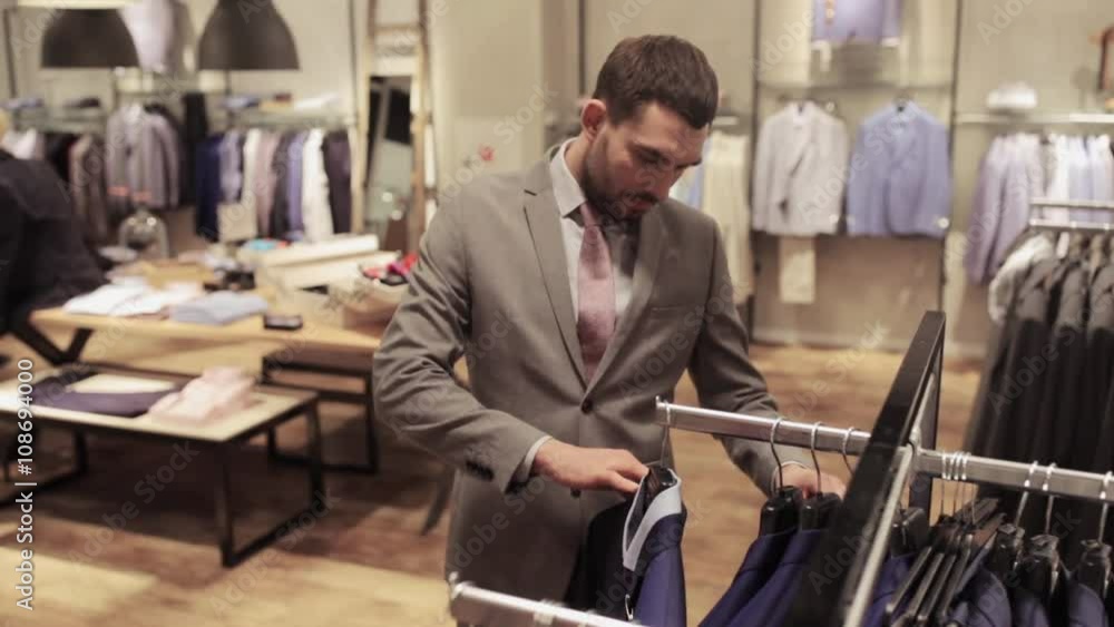 young man choosing clothes in clothing store young man choosing clothes in clothing store