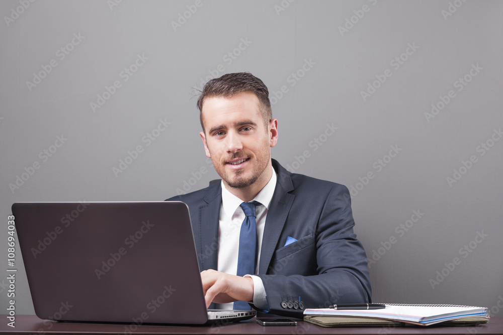 Handsome smiling business man working with laptop in office Handsome smiling business man working with laptop in office