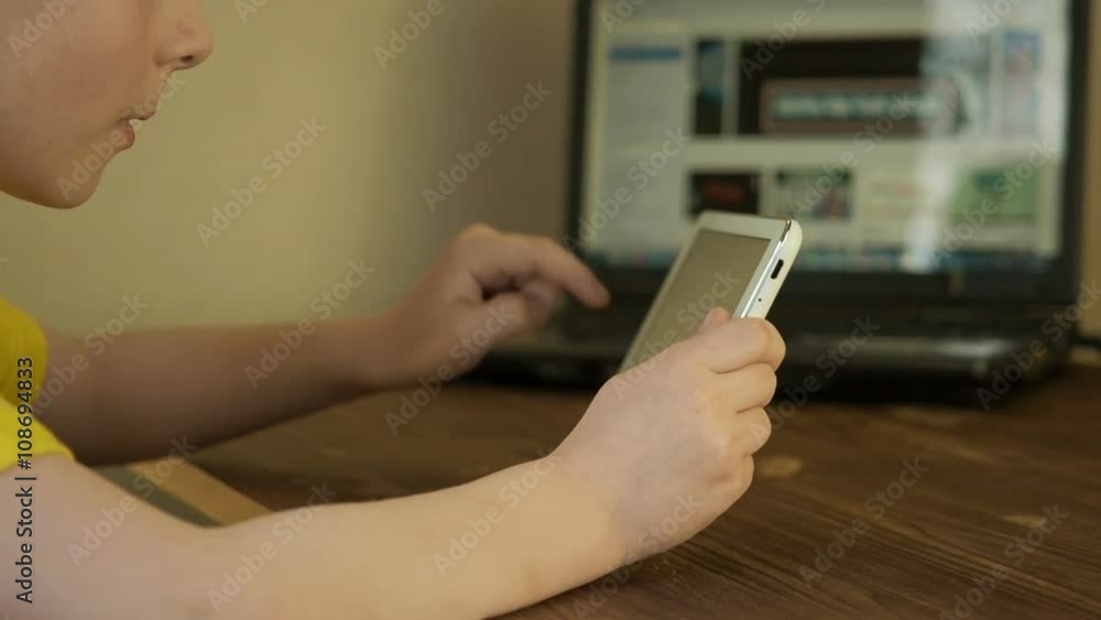 Teen boy uses a tablet PC on the table close up Teen boy uses a tablet PC on the table close up
