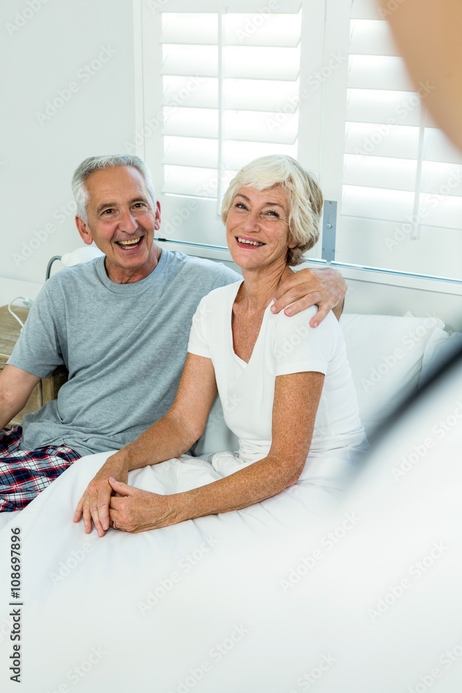 Happy senior couple sitting on bed Happy senior couple sitting on bed