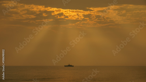 The beauty of sunrays early in the morning with coastal patrol ship and golden sea and sky background in Hua Hin , Thailand
