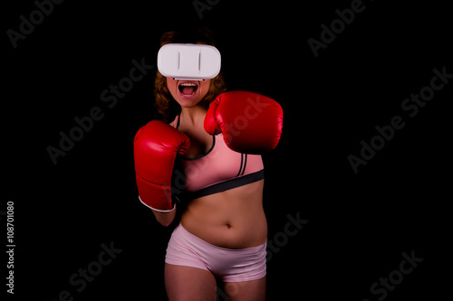 Beautiful young woman in a red boxing gloves playing in virtual reality headset