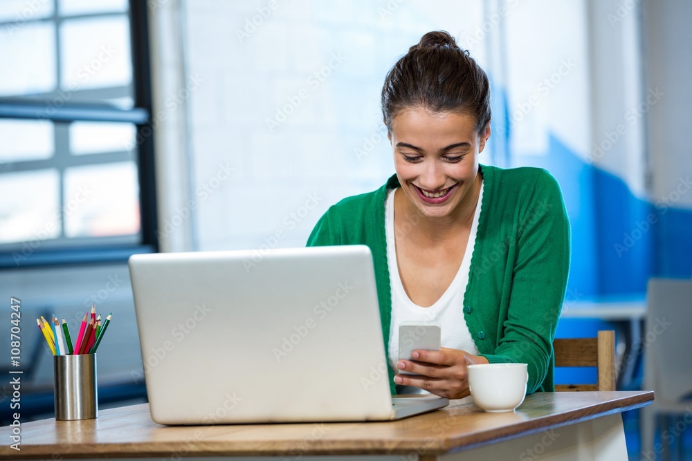 Woman using mobile phone with laptop on table Woman using mobile phone with laptop on table