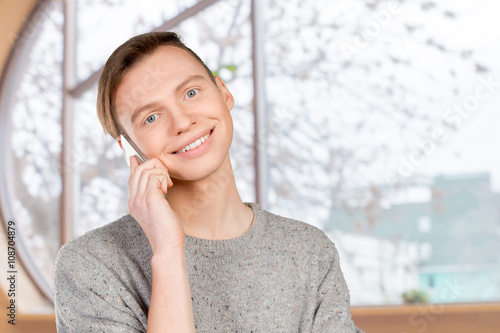 Young smiling man talking on the mobile phone