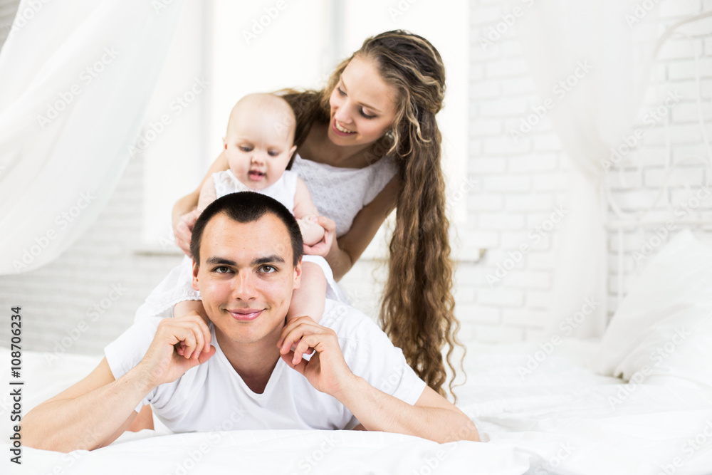 Fototapeta premium Mother and father with little baby in a bed