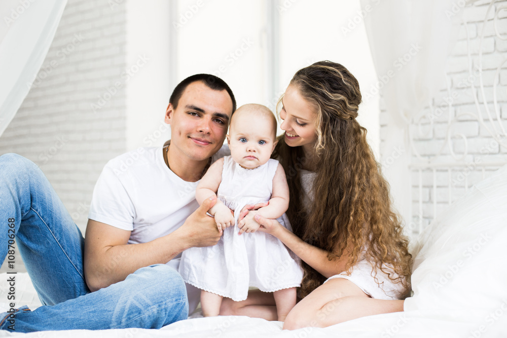 Mother and father with little baby in a bed