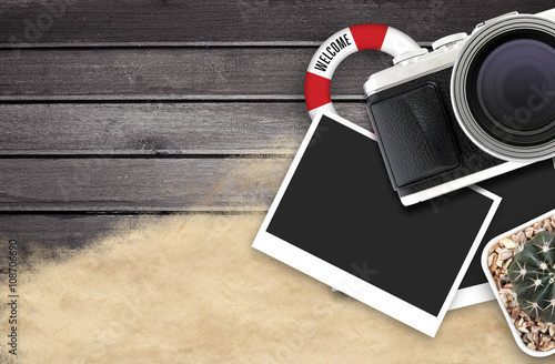 camera and blank photo frames on black wooden table. top view, travel concept