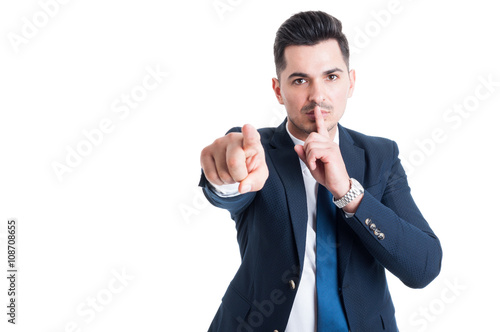 Confident businessman making keep a secret and silence gesture