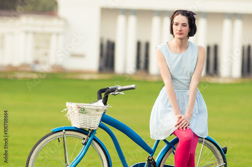 Summer activity concept with attractive woman standing on bicycl photo