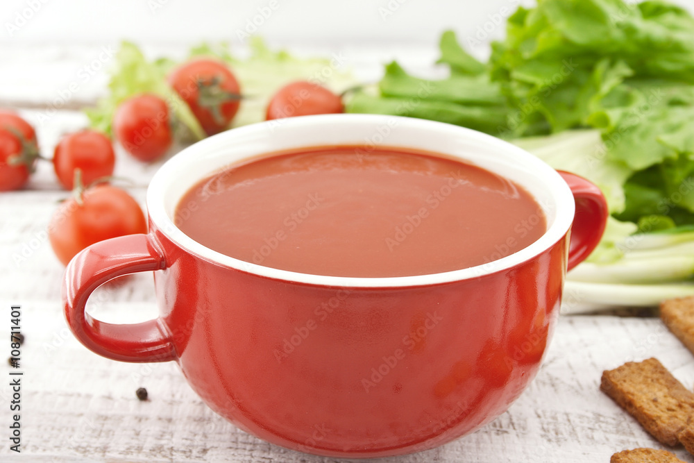 Tomato soup in red ceramic bowl on rustic wooden background. Tomato soup in red ceramic bowl on rustic wooden background.