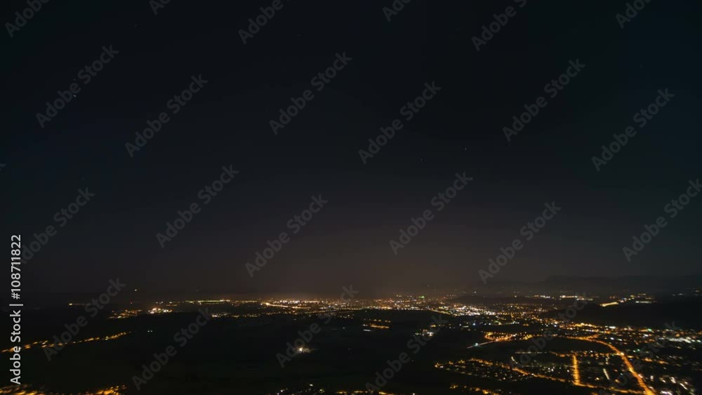 Time lapse of night life in city surrounded by mountains with stars Time lapse of night life in city surrounded by mountains with stars